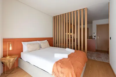 a bedroom with a white bed with a wooden headboard at Doispontozero Alegria Terracotta in Porto