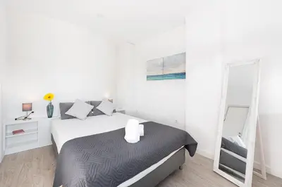a white bedroom with a bed and a mirror at GuestReady - Porto Saudade in Porto