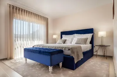 a bedroom with a blue bed and a large window at Pinheiro Cardoso in Porto