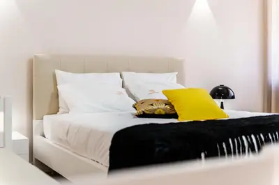 a white bed with two yellow pillows on it at Pinheiro Cardoso in Porto