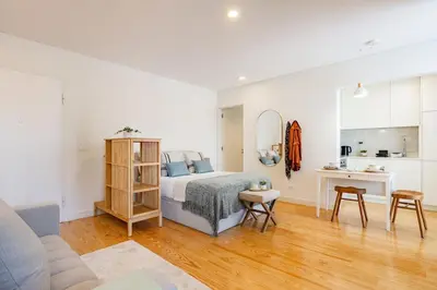 a white bedroom with a bed and a desk at Cordoaria City Studio in Porto