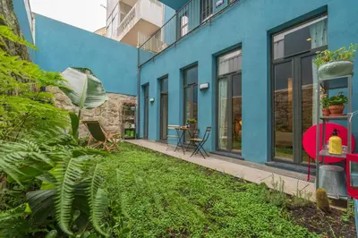 a blue building with a green yard in front of it at Host Wise - Stylish Urban Flat with Terrace in Porto