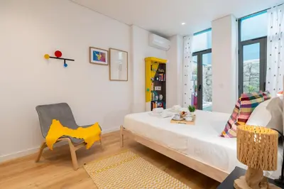 a bedroom with a bed and a chair in it at Host Wise - Stylish Urban Flat with Terrace in Porto
