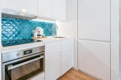 a kitchen with white cabinets and a blue accent wall at Good Vibes Only by LovelyStay in Porto