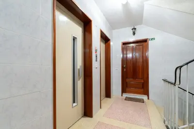 a hallway with a wooden door and a staircase at Host Wise - Bright and Elegant Urban Flat with Balcony in Porto