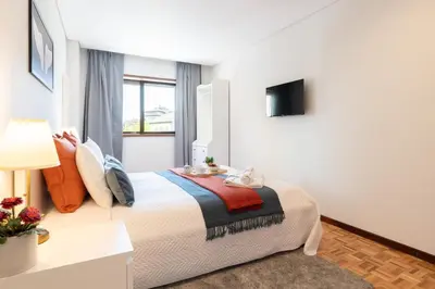 a bedroom with a large bed and a television at Host Wise - Bright and Elegant Urban Flat with Balcony in Porto