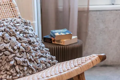 a wicker chair next to a side table with books at GuestReady - Naoki Studio in Porto
