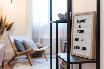 a living room with a chair and a sign on a shelf at GuestReady - Naoki Studio in Porto