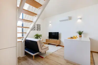 a kitchen with white cabinets and bar stools at Duque de Saldanha Duplex Loft in Porto