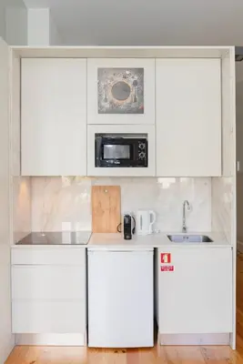 a white kitchen with white cabinets and a microwave at Liiiving in Porto - Bolhao Garden Apartment in Porto