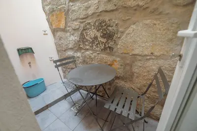 a table and chairs in front of a stone wall at Alegria Duplex by Hosty in Porto