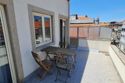 a wooden table and chairs on a balcony with a window at Tomás FLAT 4F in Porto