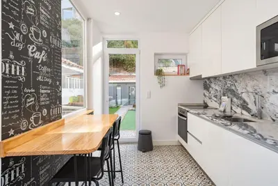 a kitchen with white cabinets and a wooden counter top at GuestReady - Le Jardin Secret in Porto