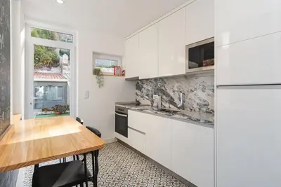 a kitchen with white cabinets and a wooden table at GuestReady - Le Jardin Secret in Porto