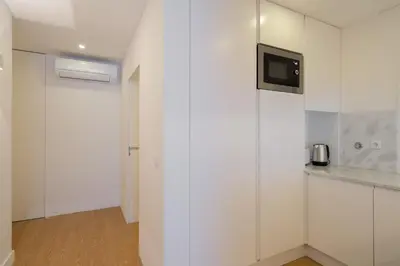a kitchen with white cabinets and a tv on a wall at GuestReady - Modern 2-Bedroom Apt in Cedofeita in Porto