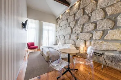 a bedroom with a stone wall and a bed and a table at GuestReady - Porto de Rio Residences in Porto