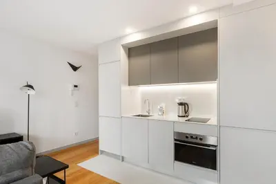 a kitchen with white cabinets and a living room at GuestReady - Trendy getaway in the heart of Porto in Porto