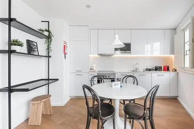 a white kitchen with a white table and chairs at GuestReady - Riverview Douro Balcony in Vila Nova de Gaia