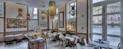 a restaurant with tables and chairs in a room with windows at NH Collection Porto Batalha in Porto
