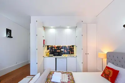 a kitchen with white cabinets and a couch in a room at Almada e Fado in Porto