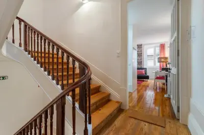 a staircase in a home with white walls and wooden floors at Almada e Fado in Porto