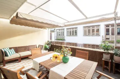 an outdoor patio with wooden tables and chairs at Fábrica Three-Story Charm by LovelyStay in Porto