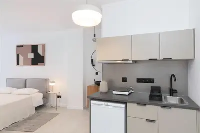 a kitchen with white cabinets and a bed in a room at Oporto Charming Studio Gaia in Vila Nova de Gaia