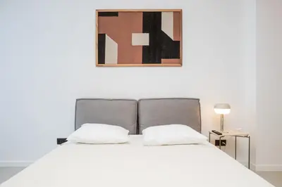 a bed with two pillows and a picture on the wall at Oporto Charming Studio Gaia in Vila Nova de Gaia