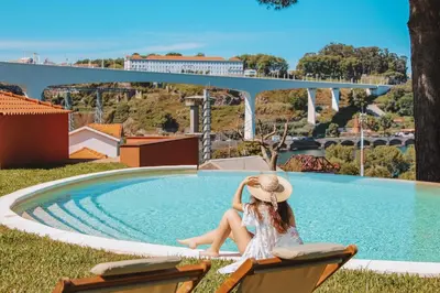 a woman in a hat sitting next to a swimming pool at The Lost Garden in Vila Nova de Gaia