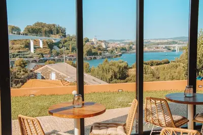 a patio with tables and chairs and a view of the water at The Lost Garden in Vila Nova de Gaia