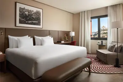 a hotel room with a bed and a chair and a window at Tivoli Kopke Porto Gaia Hotel in Vila Nova de Gaia