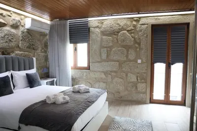 a stone walled bedroom with a bed with towels on it at Boavista Rustic House in Porto