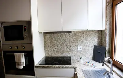 a kitchen with white cabinets and a stove top oven at Boavista Rustic House in Porto