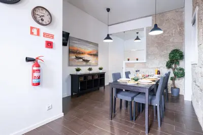 a dining room with a table and chairs and a clock at Host Wise - Cozy House w Balcony in Porto