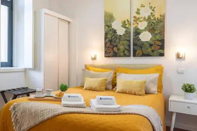 a bedroom with a yellow bed with two towels on it at Host Wise - Cozy House w Balcony in Porto