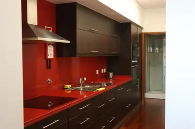 a kitchen with black cabinets and a red counter top at Estudio Metro heroismo in Porto