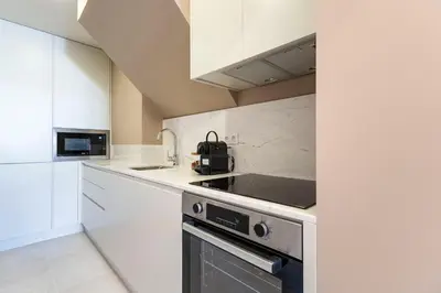 a kitchen with white cabinets and a stove top oven at ApartmentsPorto - Almada 318 in Porto