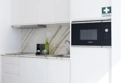 a white kitchen with a microwave and a sink at Aparts d'Avó in Porto
