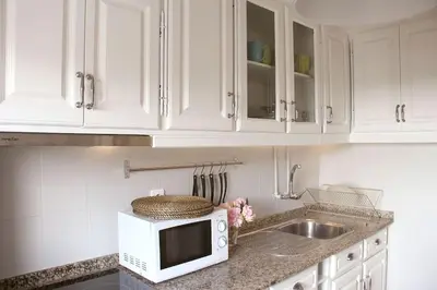 a kitchen with white cabinets and a microwave on a counter at Lulapartment in Porto