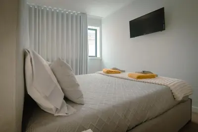 a bedroom with a bed with pillows and a television at The Cale - Antero de Quental 22 in Porto