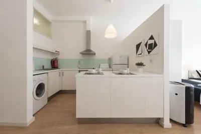 a white kitchen with a washer and dryer at BmyGuest - Santa Catarina's Loft in Porto
