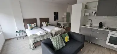 a room with two beds and a couch and a kitchen at Green Studio in Porto