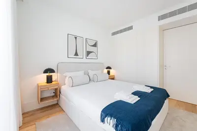 a white bedroom with a large bed with a blue blanket at GuestReady - A peaceful home near downtown in Porto