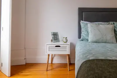 a bed with a white night stand next to a bed with a bed gmaxwell gmaxwell at A Window to Porto - Premium Studio at Clérigos Tower in Porto