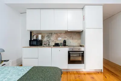 a white kitchen with white cabinets and a stove at A Window to Porto - Premium Studio at Clérigos Tower in Porto
