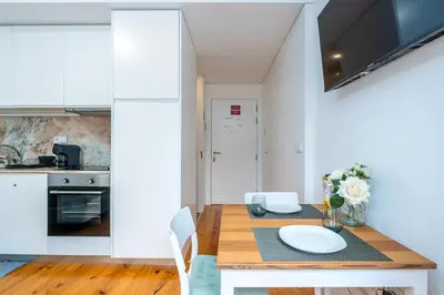 a kitchen and dining room with a wooden table at A Window to Porto - Premium Studio at Clérigos Tower in Porto