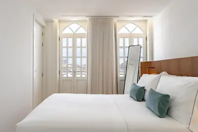 a bedroom with a white bed and two windows at Feel Porto Clerigos Charm Flats in Porto