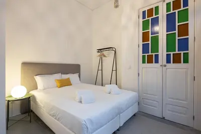 a bedroom with a white bed and a door at Trindade Premium Suites & Apartments in Porto