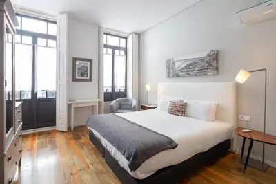 a bedroom with a large white bed and windows at Trindade Premium Suites & Apartments in Porto