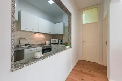a kitchen with white cabinets and a mirror on the wall at GuestReady - Cedofeita Cradle in Porto